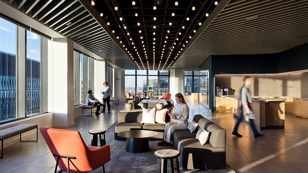 A group of people in a large room with windows and a large ceiling.